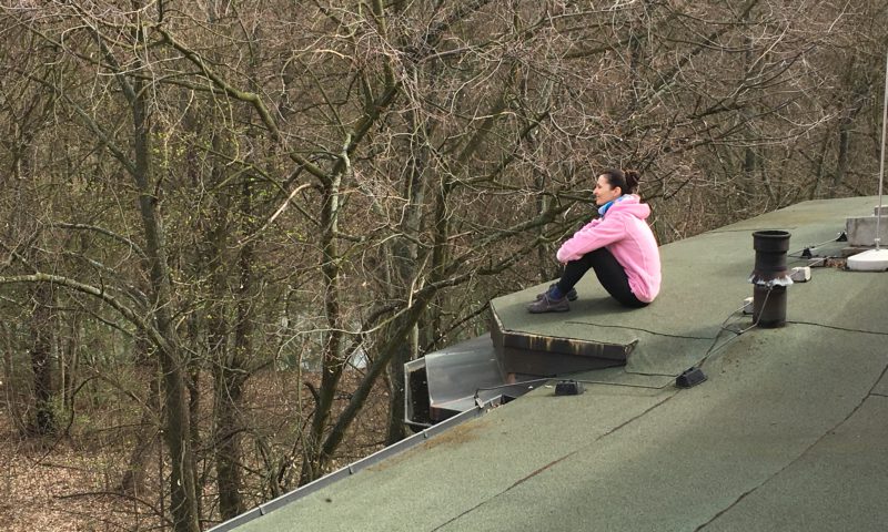 Kathrin Clara Jantke sitzt auf einem Dach und schaut sich die Gegend von oben an