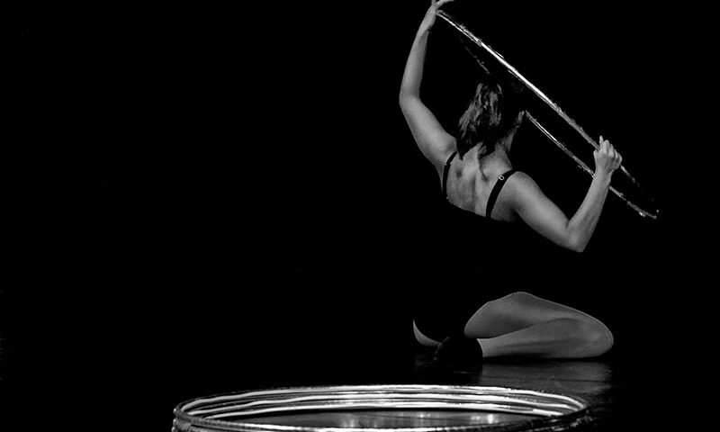 Fotografie Eine Frau in einer Gymnastik Üung mit Hula Hoop Reifen